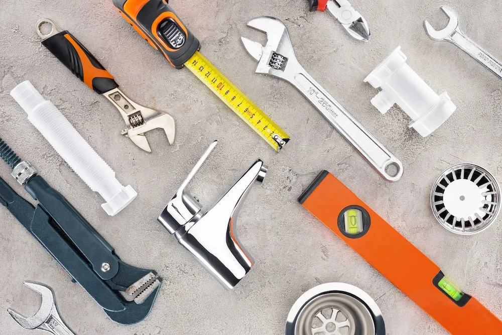 Outils de plomberie disposés sur une surface en béton