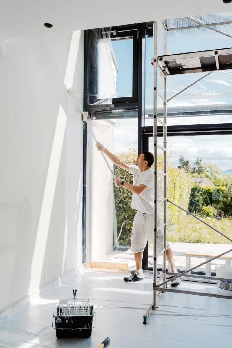 Homme repeignant les murs intérieurs d'un appartement en blanc